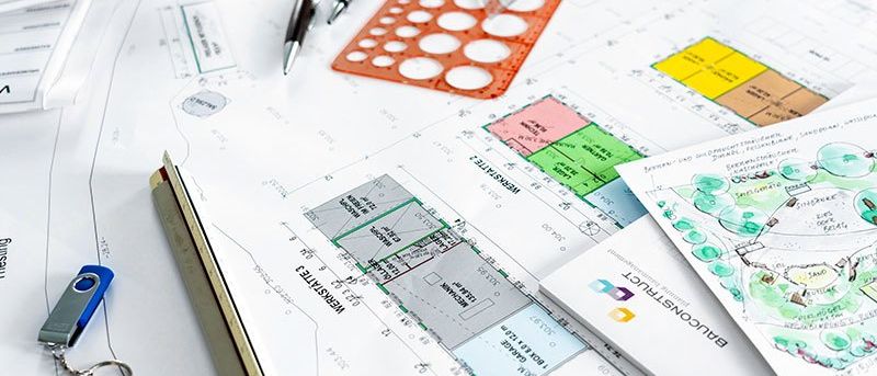 Architektonische Pläne, Blaupausen und Entwurfsskizzen auf einem Schreibtisch mit Stift, Lineal und Flash-Laufwerk.