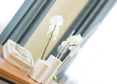 Ein Holzregal mit drei weißen dekorativen Boxen und einer weißen Orchidee im Hintergrund.