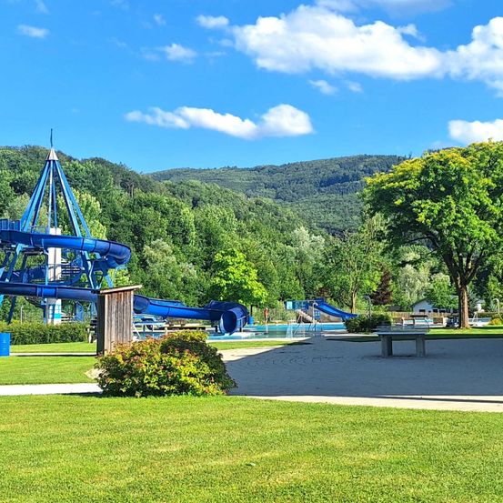 Ein Wasserpark mit einer großen blauen Rutsche und einem Pool unter einem blauen Himmel mit Wolken.