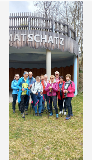 Eine Gruppe von Menschen steht vor einem Holzgebäude mit dem Namen Matschatz. Sie halten Skistöcke in der Hand und scheinen für ein Foto zu posieren.