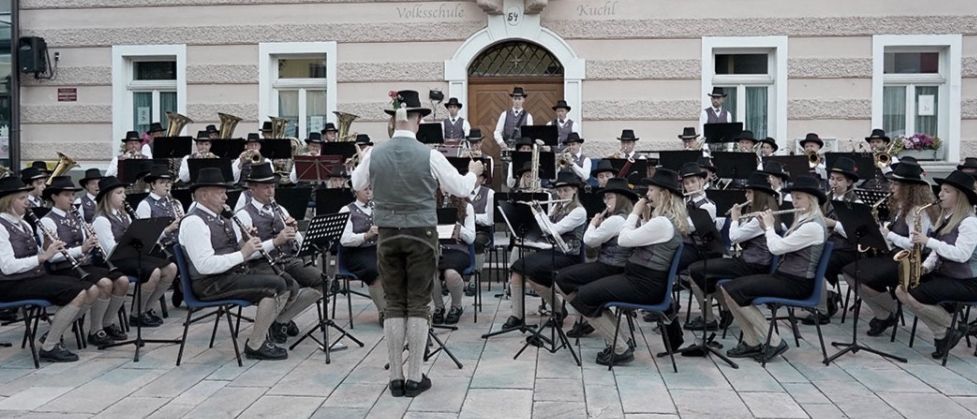 Ein Musikorchester spielt auf der Straße. Über der Band steht 'Marktkonzerte'. Drei Konzertdaten sind aufgeführt. Die Konzerte beginnen um 20 Uhr.
