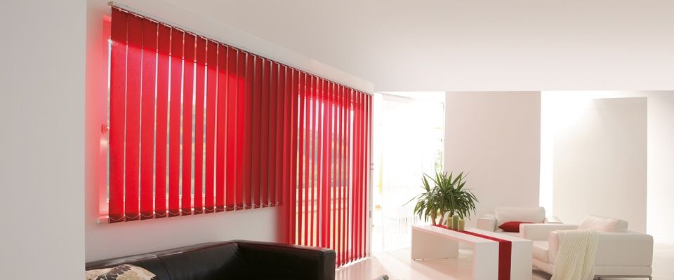 Ein modernes Wohnzimmer mit roten Jalousien, einem weißen Sofa, einem Couchtisch und einer Pflanze an der Seite.