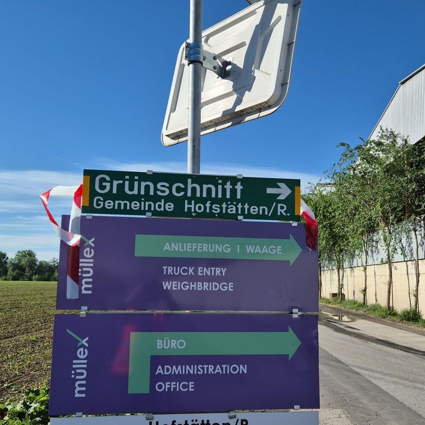Ein Schild weist auf Gruenschnitt Gemeinde Hofstaetten/R hin, mit Pfeilen auf den LKW-Eingang und die Waage. Ein weiteres Schild zeigt das Büro und das Verwaltungsbüro an.