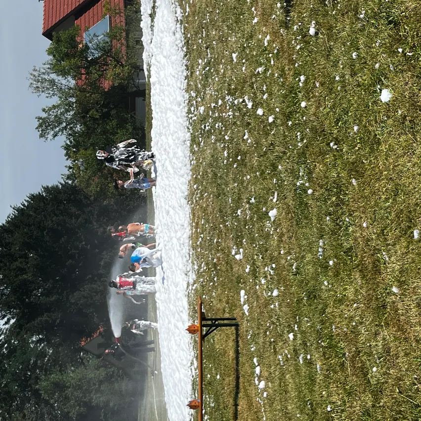 Eine Gruppe von Menschen steht in einem schneebedeckten Feld, einige sprühen Wasser aus einem Schlauch.