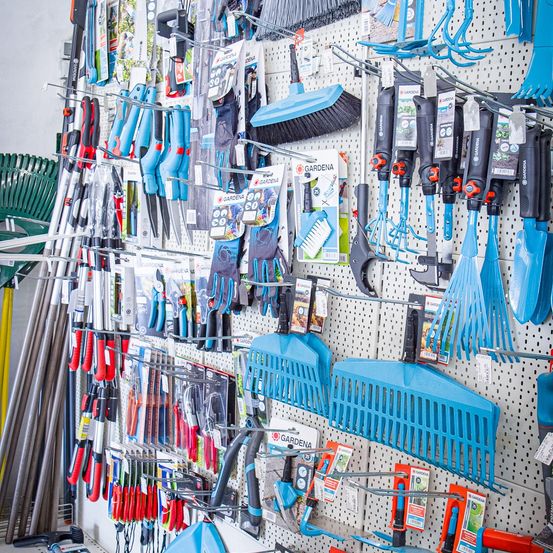 Ein Gartenladen mit einer Vielzahl von Gartenwerkzeugen auf einem Pegboard, einschließlich Rechen, Schaufeln und Handschuhen.