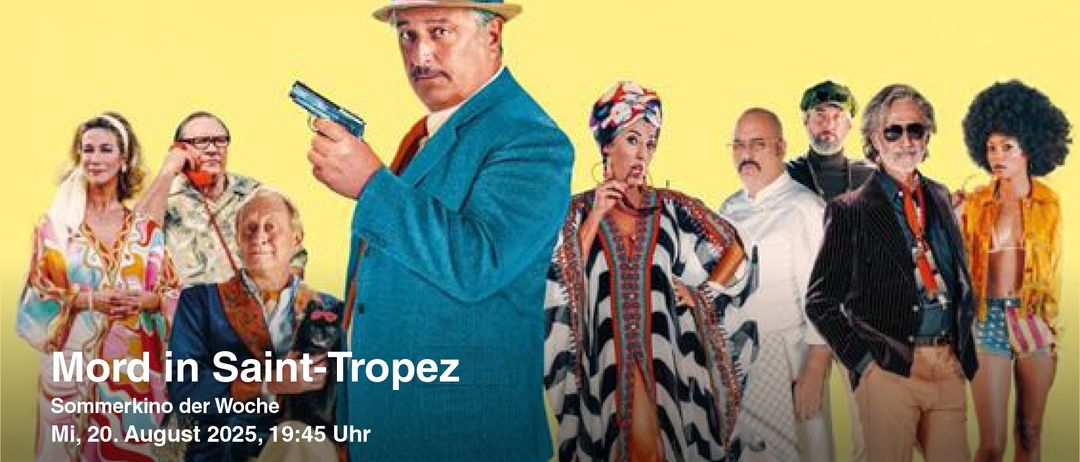 Ein Mann in einem blauen Anzug, der eine Pistole in der Hand hält, steht neben einer Frau in einem schwarz-weißen Kleid und einem Turban. Hinter ihnen stehen auch andere Personen. Die Zeit ist 19:45 Uhr.