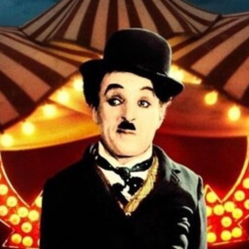 Ein Mann in formeller Kleidung, einschließlich eines Zylinderhuts, posiert vor einem beleuchteten Zirkuszelt mit einer beleuchteten Markise.