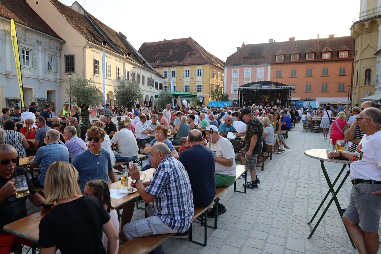 Fest in Leibnitz: Viele Menschen sitzen bei Musik und gutem Wetter auf Bänken und Tischen im Freien.