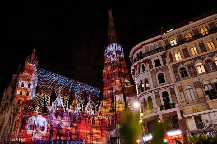 Eine Kathedrale wird nachts mit einer Schädelprojektion beleuchtet. Das Gebäude ist mit komplizierten Designs und leuchtenden Farben verziert.
