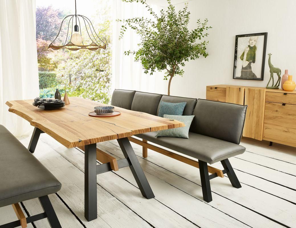 Ein moderner Essbereich mit einem Holztisch, einer Eckbank und einem Topf. Der Raum hat weiße Wände und Holzböden.