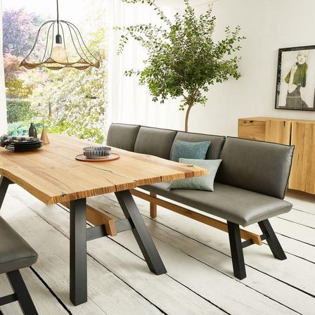 Ein moderner Essbereich mit einem Holztisch, einer Eckbank und einem Topf. Der Raum hat weiße Wände und Holzböden.