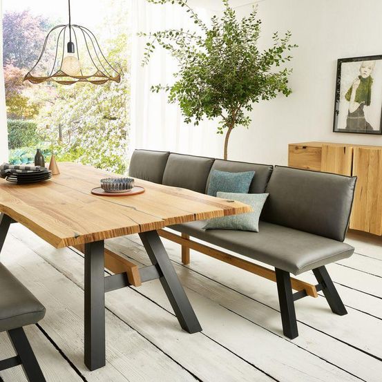 Ein moderner Essbereich mit einem Holztisch, einer Eckbank und einem Topf. Der Raum hat weiße Wände und Holzböden.