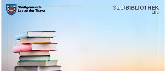 Ein Stapel bunter Bücher vor einem blauen Himmelshintergrund. Die Bücher sind auf einer Holzoberfläche platziert. Der Text 'StadtBThaya' ist in der oberen rechten Ecke angezeigt.