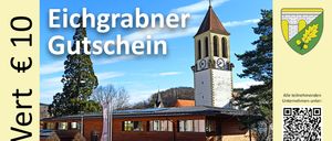 Ein Gebäude mit Solardach und einem Uhrturm im Hintergrund, unter einem blauen Himmel mit Wolken. Das Gebäude hat viele Fenster und ein Schild mit der Aufschrift 'Privatparkplatz'.