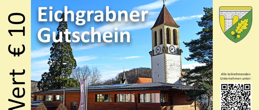 Ein Gebäude mit Solardach und einem Uhrturm im Hintergrund, unter einem blauen Himmel mit Wolken. Das Gebäude hat viele Fenster und ein Schild mit der Aufschrift 'Privatparkplatz'.