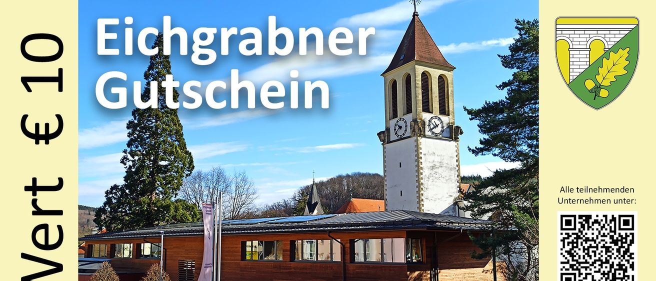 Ein Gebäude mit Solardach und einem Uhrturm im Hintergrund, unter einem blauen Himmel mit Wolken. Das Gebäude hat viele Fenster und ein Schild mit der Aufschrift 'Privatparkplatz'.