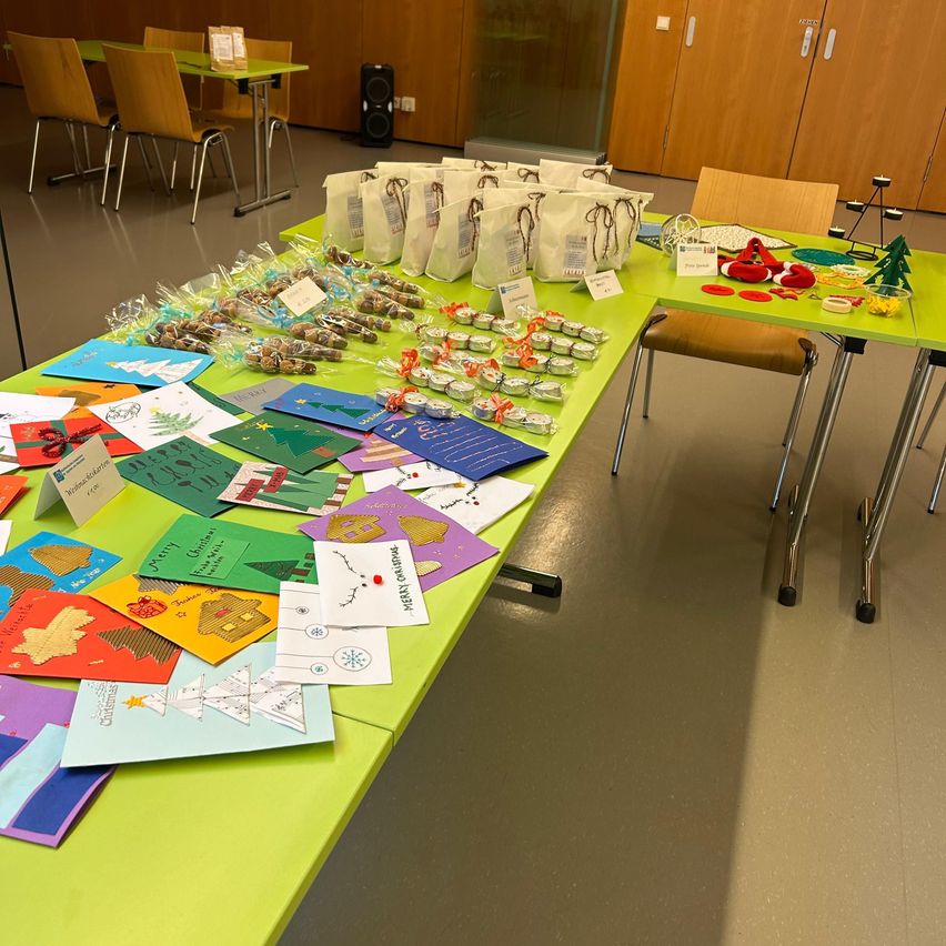 A room with green tables holding bags and gift items, handmade cards, and decorations.
