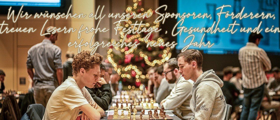 Mehrere Spieler sind in einem Raum in einer Schachpartie engagiert. Einige Spieler schauen auf das Brett, während andere nach unten schauen. Der Raum hat einen Weihnachtsbaum und einen Monitor. Die Spieler sitzen auf Stühlen um einen Tisch mit einem Schachbrett.
