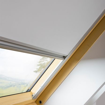 Ein Nahaufnahme eines hölzernen Dachbodenfensters mit Metallrahmen, das die schräge Glasscheibe und die hölzerne Umrandung des Fensters zeigt.