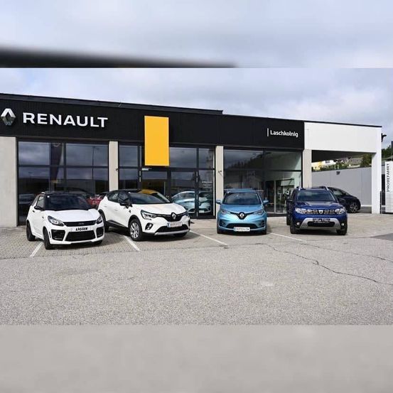 Vier Renault Autos sind vor einem Renault-Händler geparkt, mit einem bewölkten Himmel im Hintergrund.
