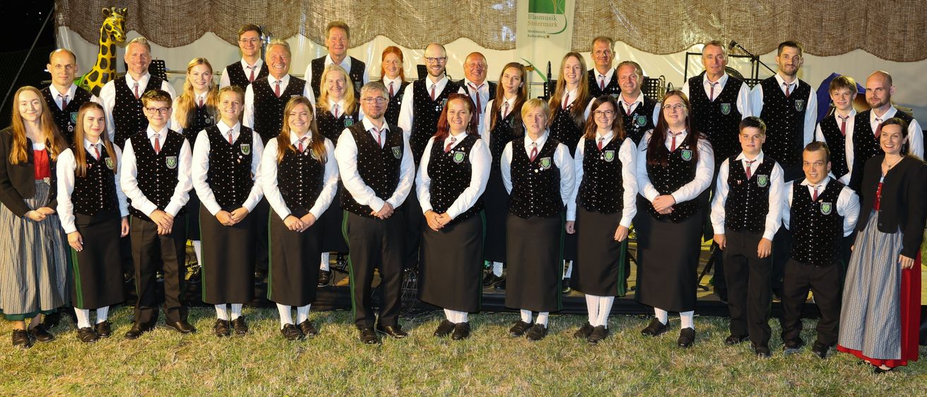 Eine Gruppe von Menschen in passenden Westen und Röcken, die vor einem Zelt stehen, lächeln und für ein Foto posieren.