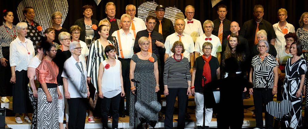 Eine Gruppe von Menschen, darunter Männer und Frauen, steht auf einer Bühne. Sie sind alle in formeller Kleidung und einige tragen Krawatten. Sie alle schauen in die gleiche Richtung, möglicherweise für ein Foto posieren.