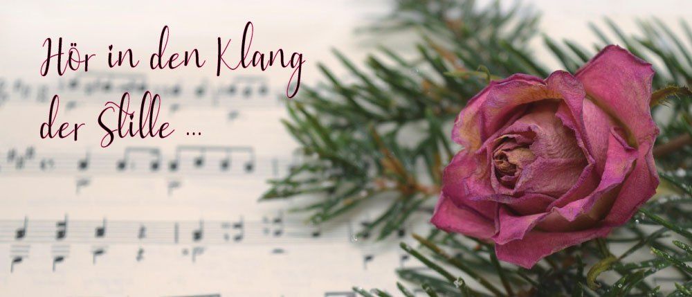 Eine rosa Rose und Tannennadeln liegen auf einem Musikblatt mit dem Text 'In den Klang Stille' in Lila geschrieben.