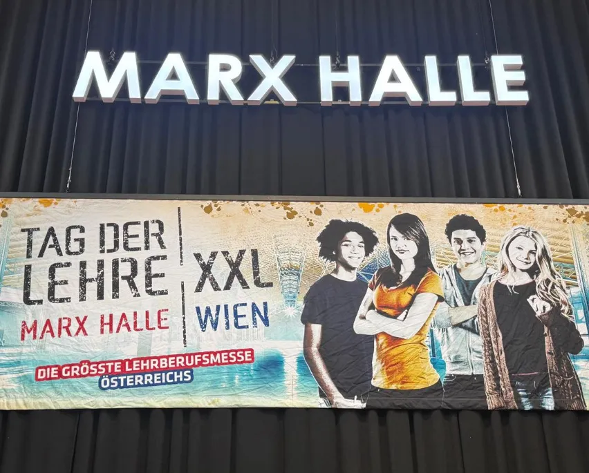 Banner für die größte Lehrberufsmesse Österreichs mit einer Gruppe junger Menschen. Darunter steht 'MARX HALL' beleuchtet.
