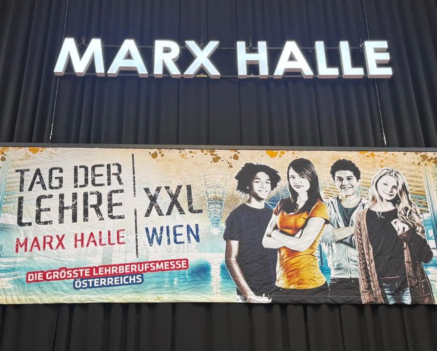 Banner für die größte Lehrberufsmesse Österreichs mit einer Gruppe junger Menschen. Darunter steht 'MARX HALL' beleuchtet.