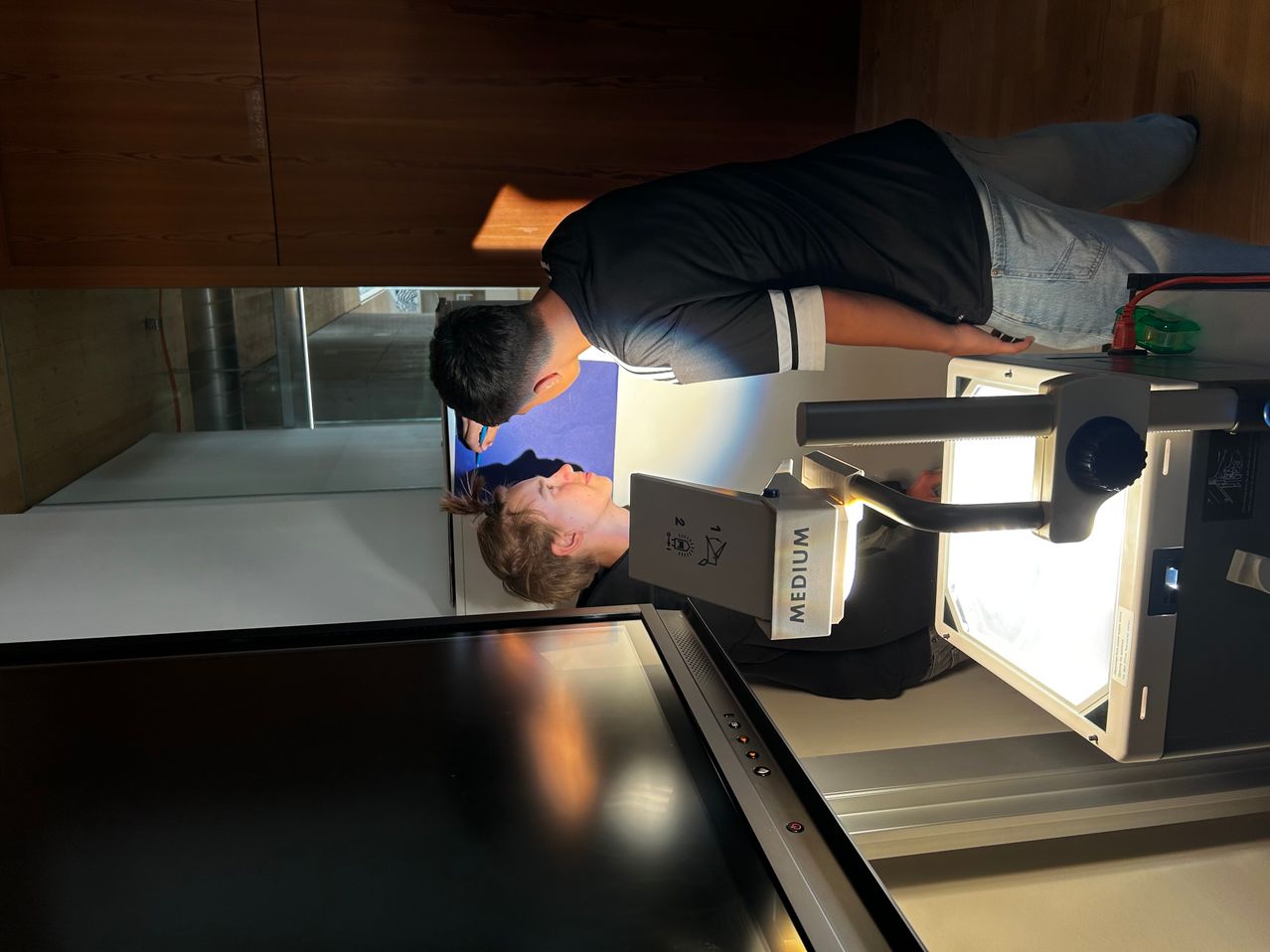 A person is using a dental mirror to examine another person's teeth while a bright light illuminates the area.