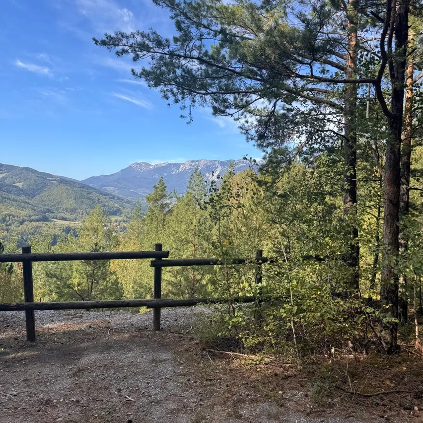 Ein landschaftlicher Blick auf eine Gebirgslandschaft mit einem Holzzaun im Vordergrund.
