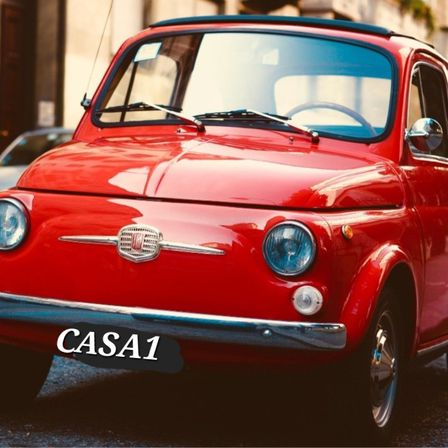 Ein roter Oldtimer mit dem Wort CASA1 auf dem vorderen Stoßfänger ist auf einer Straße geparkt. Die Scheinwerfer und der Kühlergrill des Autos sind sichtbar.