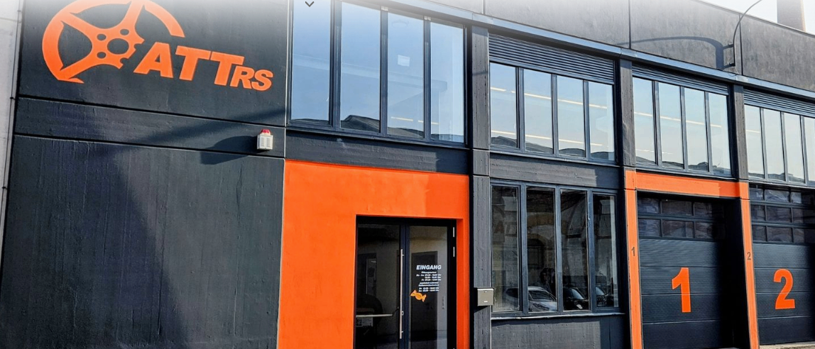 Das Äußere eines modernen Gebäudes mit schwarzem und orangefarbenem Design, mit großen Fenstern, einer Tür mit Glasscheibe und der Nummer 1 an der Garagentür.