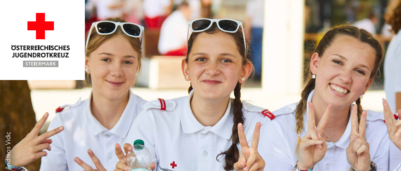 Vier junge Frauen in weißen Uniformen lächeln und posieren für ein Foto mit Friedenszeichen. Darunter steht Landesjugendbewerb 20. JUNI 2026 in Stainz.