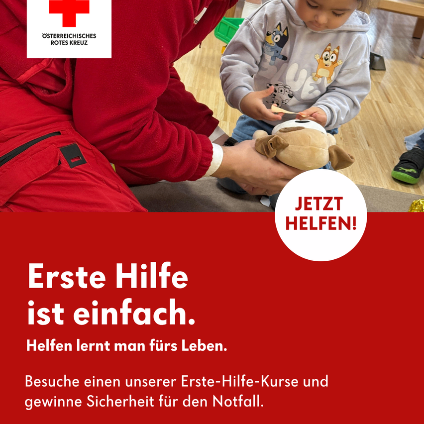 A person in red first aid clothing is teaching a child how to use a first aid kit. The child is holding a stuffed toy.