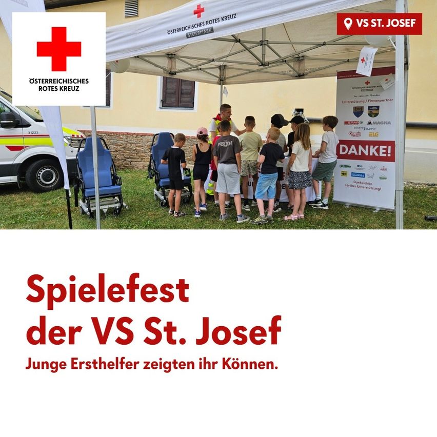 Eine Gruppe von Kindern und Erwachsenen versammelt sich unter einem Zelt mit einem roten Kreuz-Logo, möglicherweise für eine Erste-Hilfe-Veranstaltung. Das Schild lautet 'Spielefest der VS St. Josef.'