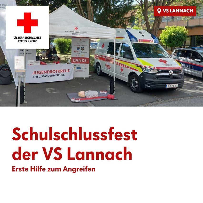 Ein Krankenwagen ist neben einem Zelt mit einem roten Kreuzlogo geparkt, in der Nähe eines Gebäudes. Ein Mannequin liegt auf dem Boden mit einem Tisch, auf dem Jugendrotkreuz steht. Die Veranstaltung heißt Schulschlussfest der VS Lannach.