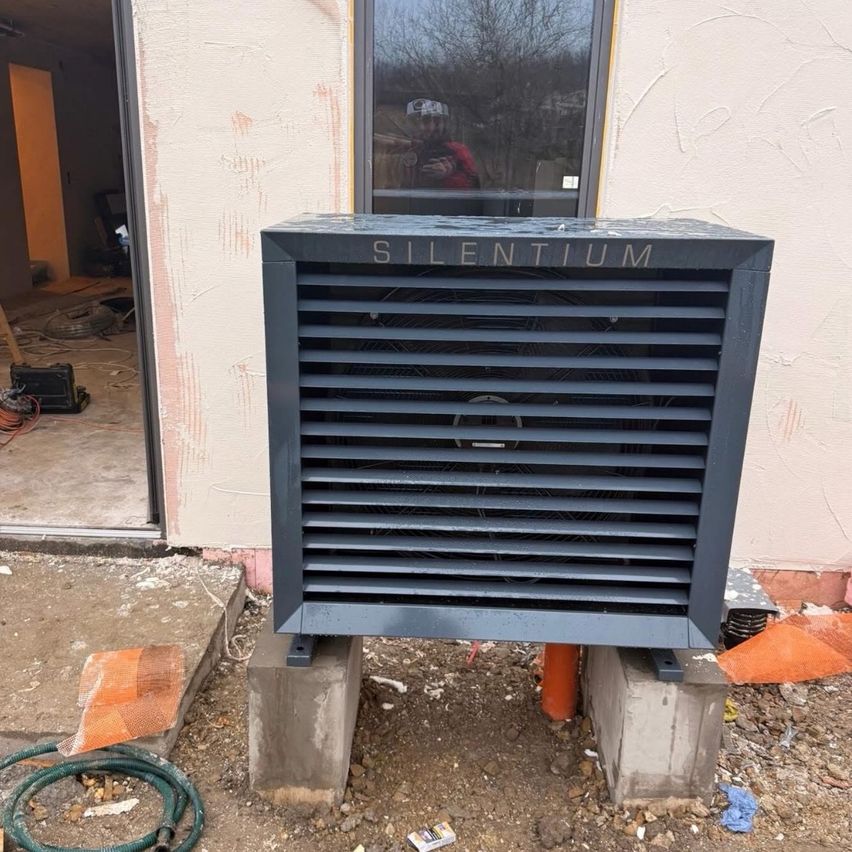 Ein schwarzes Gerät mit der Aufschrift 'SILENTIUM' steht vor einem Gebäude. Das Gebiet befindet sich im Bau.