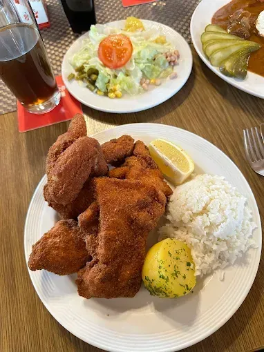 Eine Mahlzeit mit gebratenem Huhn, Reis und Salat. Ein Glas Bier und eine Zitrone auf der Seite.