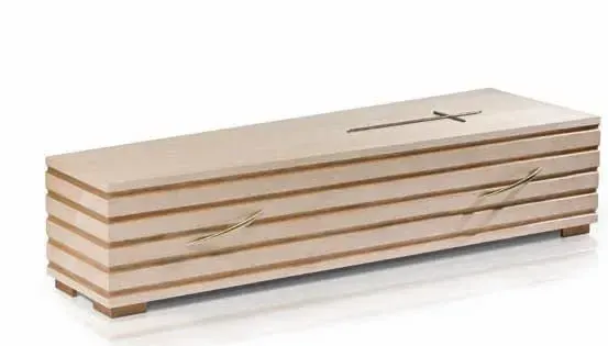 Ein beigefarbener Holzsarg mit einem Kreuz auf der Oberseite und zwei Metallgriffen. Es ist ordentlich in einer Reihe gestapelt und auf einer weißen Oberfläche platziert.