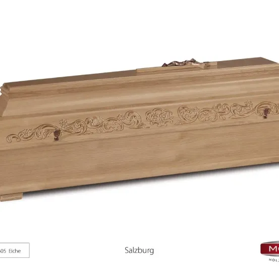 Ein hölzerner Sarg mit Blumenmustern an der Seite, beschriftet mit '05 Eiche' und 'Salzburg'. Er hat einen Messinggriff oben.