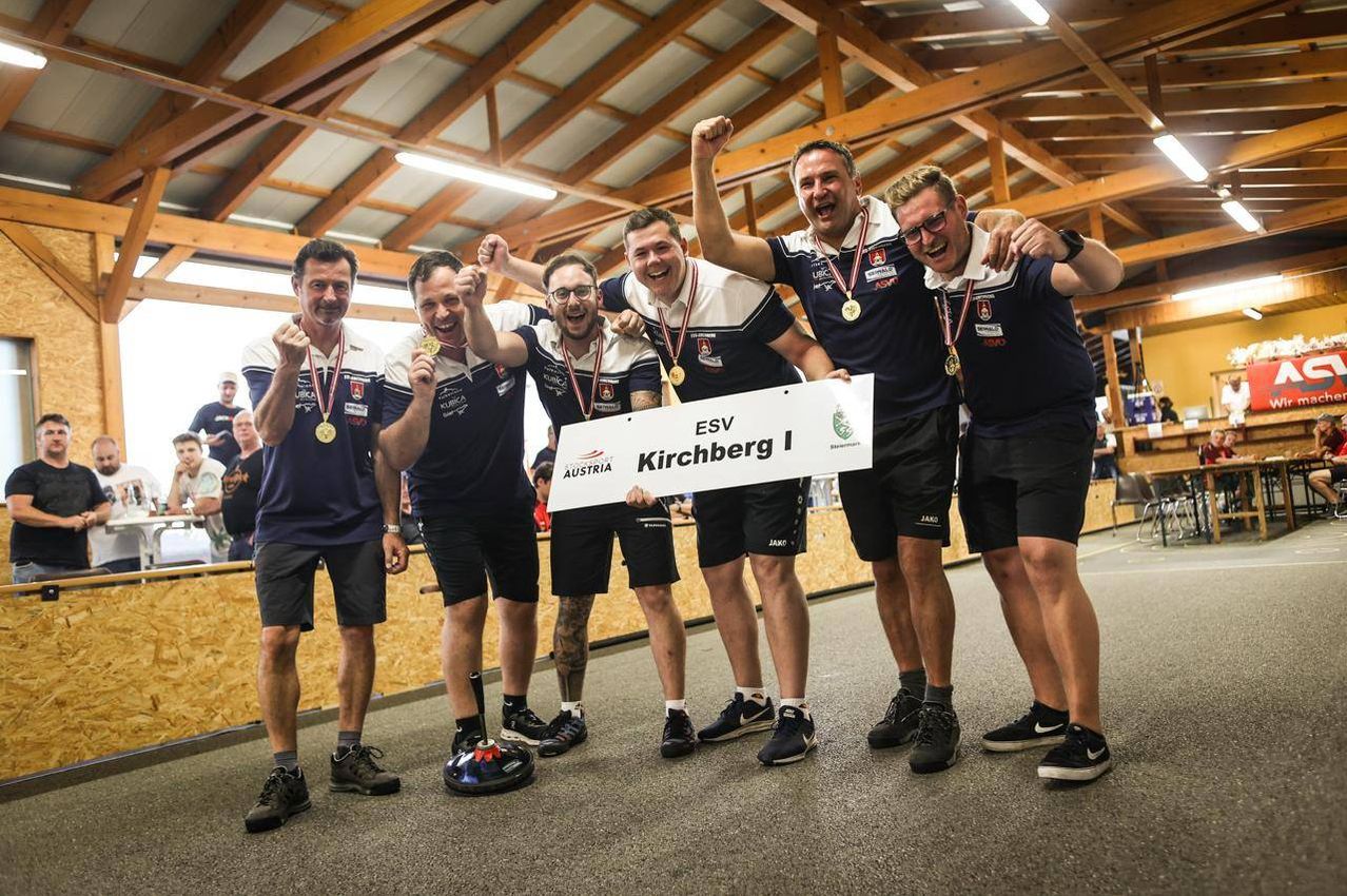 Gruppe von Männern, die ein Banner halten und den Sieg bei einer Sportveranstaltung feiern, mit Medaillen um den Hals.
