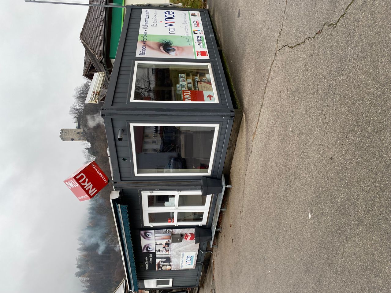 Ein Gebäude mit Werbung für einen Friseursalon an der Straßenseite. Ein rotes Schild mit dem Wort 'INK' ist über dem Gebäude.
