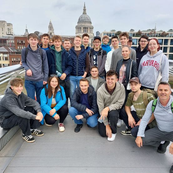 Eine Gruppe junger Menschen posiert für ein Foto auf einer Brücke in London, mit der St. Paul's Cathedral im Hintergrund.