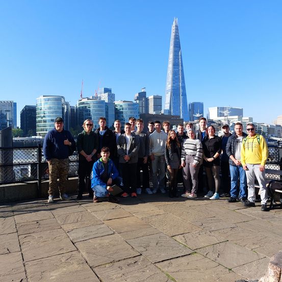 Eine Gruppe von Menschen posiert für ein Foto mit der Skyline von London im Hintergrund, darunter der Shard-Skyscraper.