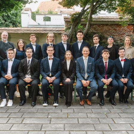 Eine Gruppe schick gekleideter junger Leute posiert für ein Foto vor einer Ziegelwand.
