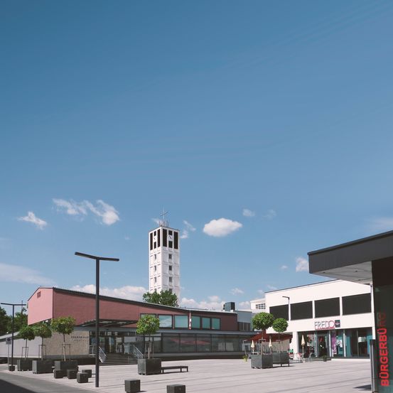 Ein klarer blauer Himmel mit einigen Wolken. Ein hoher weißer Turm steht in der Mitte des Bildes, umgeben von Gebäuden und Bäumen.