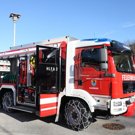 Ein roter und weißer Feuerwehrwagen mit der Aufschrift HLA 2 steht auf einem offenen Gelände.