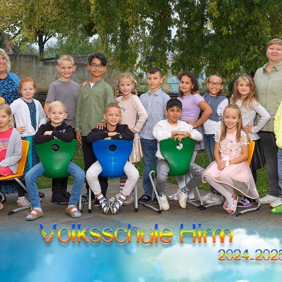 Eine Gruppe von Kindern und Erwachsenen posiert für ein Foto an der Volksschule Himm, das Bild hat einen Wasserzeichen mit den Jahren 2024-2025.