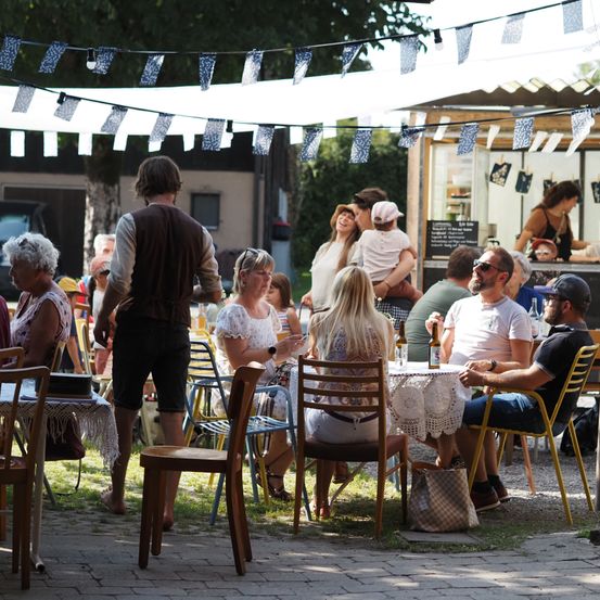 Eine Gruppe von Menschen trifft sich in einem Park im Freien mit Food Trucks und Dekorationen.